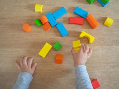 Two small hands play with colorful wooden blocks