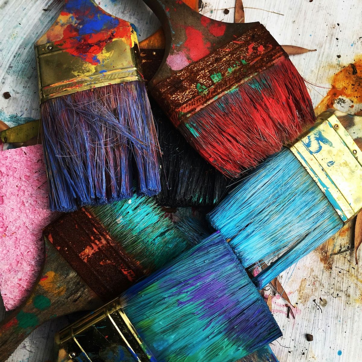 Stacked paintbrushes of various bright colors drying.